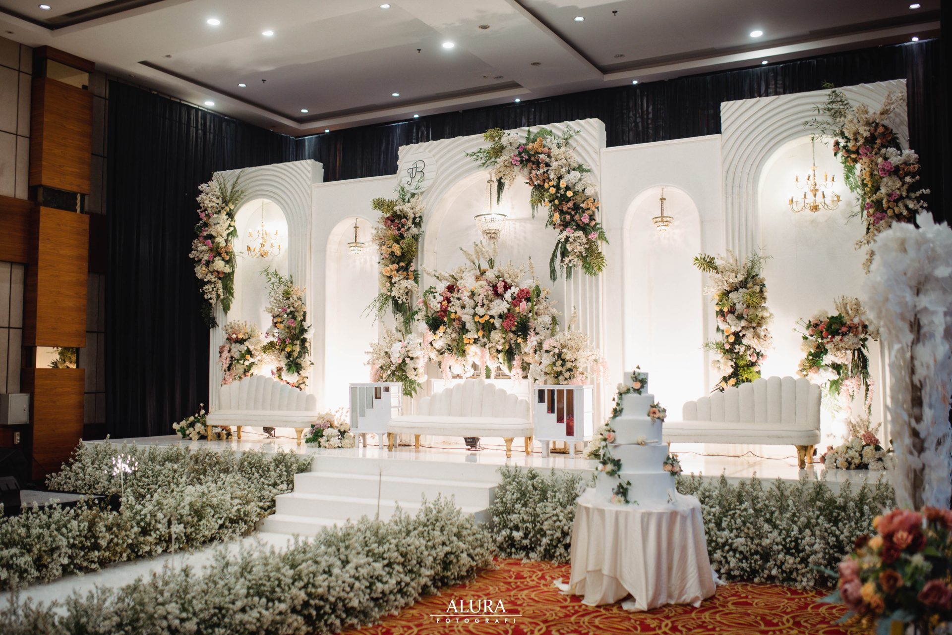 Pelaminan ballroom mewah dengan dekorasi putih dan emas