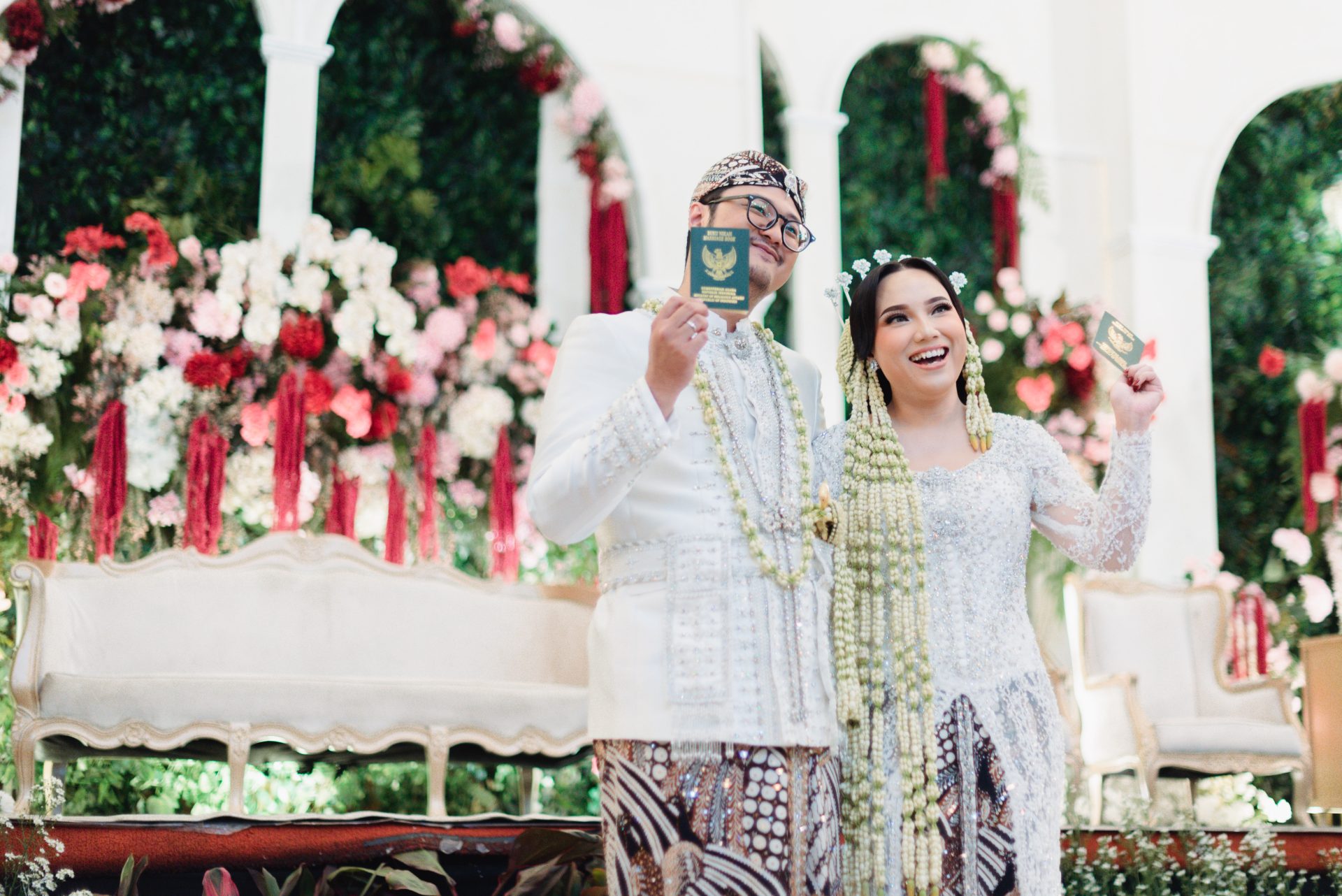 Pengantin adat Jawa menunjukkan buku nikah